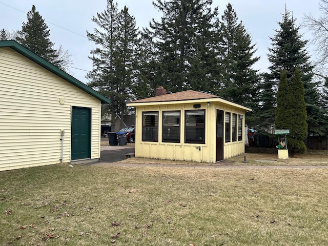 back of house featuring a yard, roof with shingles, a chimney, and board and batten siding