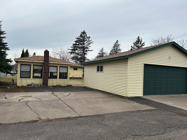view of front facade featuring an outbuilding, a chimney, and a garage