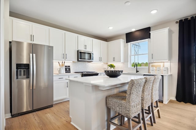 15071 Athgoe Dr, Rosemount, MN 55068 - kitchen featuring appliances with stainless steel finishes, white cabinets, light countertops, light wood-style flooring, and a breakfast bar