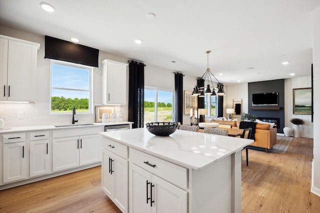 15071 Athgoe Dr, Rosemount, MN 55068 - kitchen with a sink, a center island, light wood-style flooring, hanging light fixtures, and white cabinetry