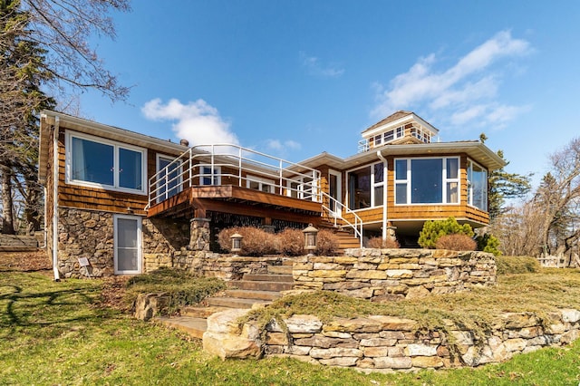back of property featuring a sunroom, a wooden deck, stairs, and stone siding