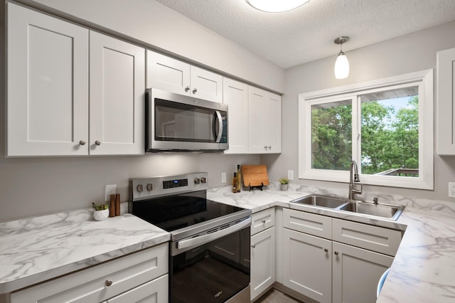 21485 Inwood Ave N, Forest Lake, MN 55025 - kitchen with stainless steel appliances, a sink, a textured ceiling, white cabinetry, and light stone countertops