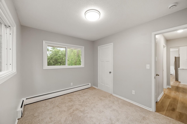 21485 Inwood Ave N, Forest Lake, MN 55025 - unfurnished bedroom featuring a baseboard radiator, baseboards, carpet flooring, and a textured ceiling