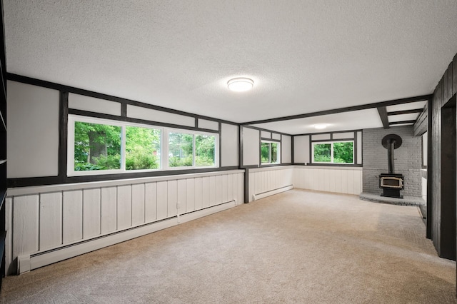21485 Inwood Ave N, Forest Lake, MN 55025 - unfurnished room featuring a textured ceiling, a baseboard radiator, carpet, a wood stove, and wainscoting