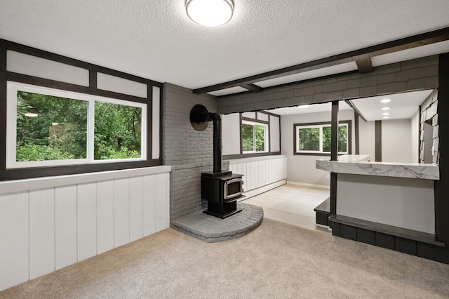 21485 Inwood Ave N, Forest Lake, MN 55025 - unfurnished living room with a wood stove, carpet floors, a textured ceiling, and beam ceiling