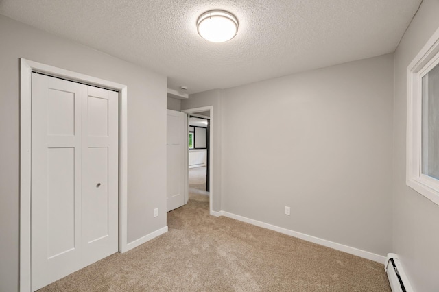 21485 Inwood Ave N, Forest Lake, MN 55025 - unfurnished bedroom featuring a baseboard heating unit, light colored carpet, a textured ceiling, baseboards, and a closet