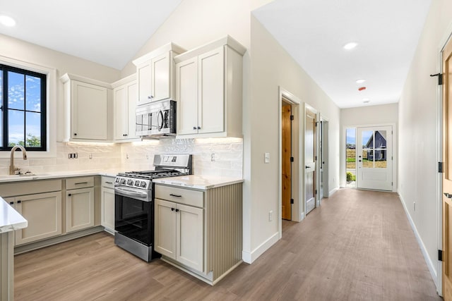 25882 Emerson Ct, Wyoming, MN 55092 - kitchen with light wood-style flooring, a sink, stainless steel appliances, a healthy amount of sunlight, and backsplash