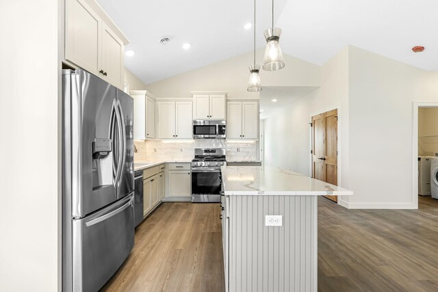 25882 Emerson Ct, Wyoming, MN 55092 - kitchen with a center island, appliances with stainless steel finishes, decorative backsplash, and wood finished floors