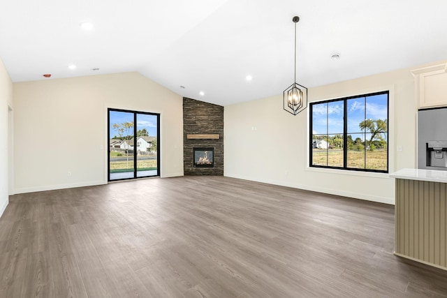 25882 Emerson Ct, Wyoming, MN 55092 - unfurnished living room with wood finished floors, lofted ceiling, and a stone fireplace