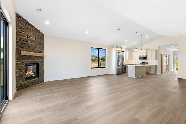 25882 Emerson Ct, Wyoming, MN 55092 - unfurnished living room featuring a stone fireplace, light wood-style floors, and a healthy amount of sunlight