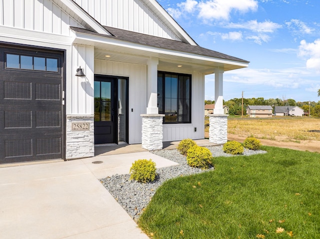 25882 Emerson Ct, Wyoming, MN 55092 - view of exterior entry with stone siding, a lawn, a shingled roof, board and batten siding, and a porch