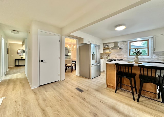 809 Wagon Wheel Trl, Mendota Heights, MN 55120 - kitchen with visible vents, a breakfast bar, wall chimney range hood, backsplash, and stainless steel appliances