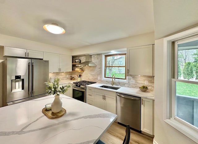 809 Wagon Wheel Trl, Mendota Heights, MN 55120 - kitchen featuring backsplash, appliances with stainless steel finishes, a sink, light stone counters, and wall chimney exhaust hood