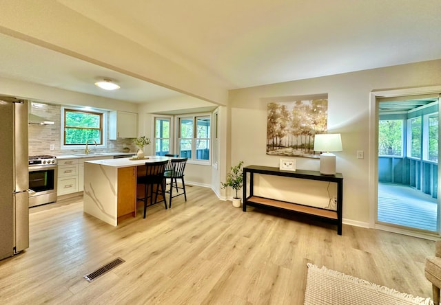 809 Wagon Wheel Trl, Mendota Heights, MN 55120 - kitchen featuring a sink, a kitchen breakfast bar, wall chimney exhaust hood, stainless steel appliances, and visible vents