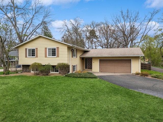 tri-level home with fence, an attached garage, driveway, and a front yard