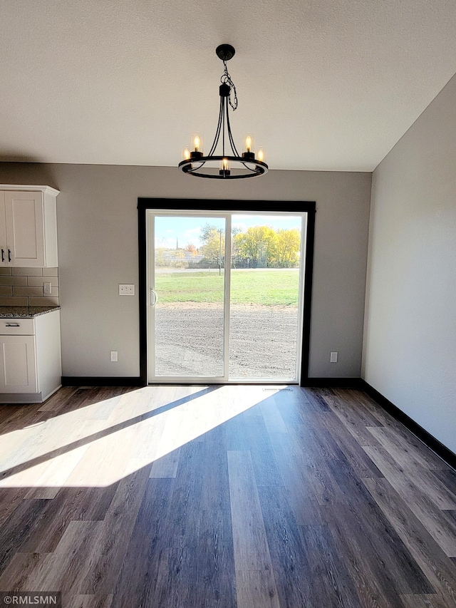 unfurnished dining area with baseboards, wood finished floors, and a notable chandelier