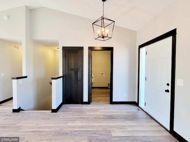 entrance foyer with visible vents, light wood-style floors, lofted ceiling, and a chandelier
