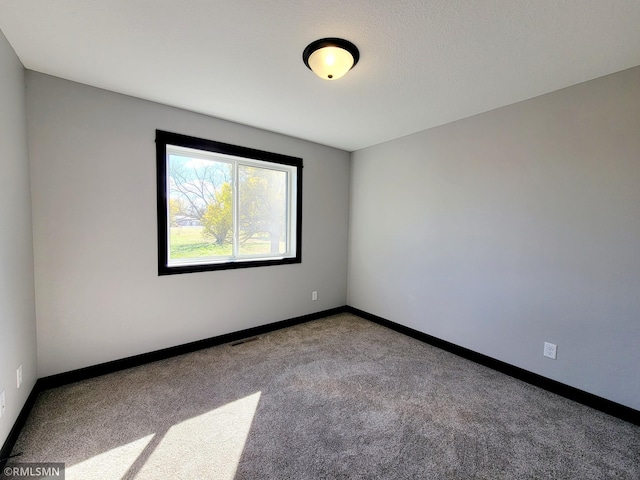 carpeted empty room featuring baseboards and visible vents