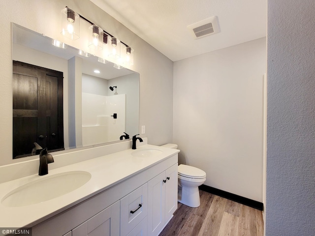 bathroom featuring walk in shower, toilet, visible vents, and a sink
