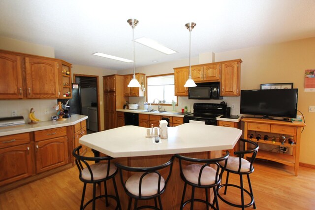 932 Spruce Ave S, Thief River Falls, MN 56701 - kitchen with light wood-style flooring, washer / dryer, a sink, and black appliances