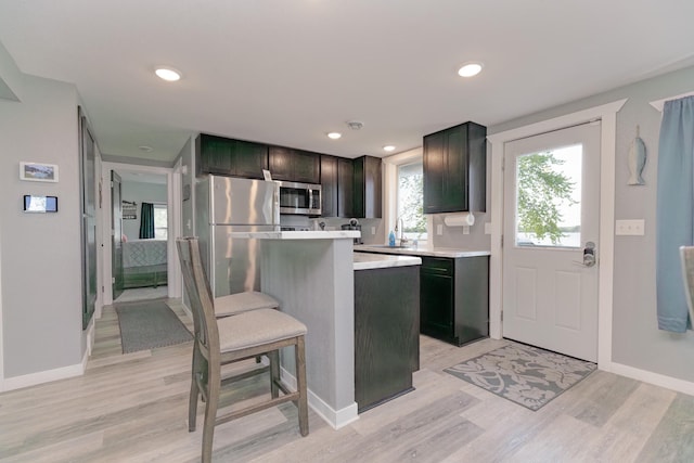 43 Blue Stem Rd, Shetek Twp, MN 56175 - kitchen featuring appliances with stainless steel finishes, light countertops, light wood-style flooring, a kitchen breakfast bar, and baseboards
