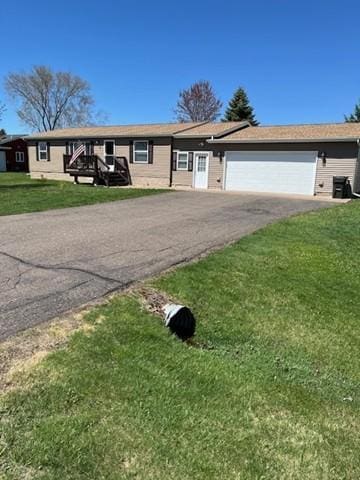ranch-style home featuring an attached garage, a front lawn, and aphalt driveway
