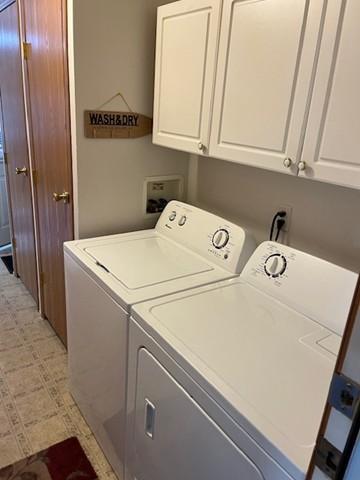 laundry area featuring light floors, washing machine and dryer, and cabinet space