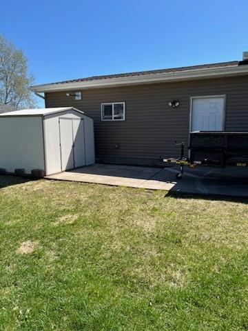 back of house with an outbuilding, a yard, a shed, and a patio