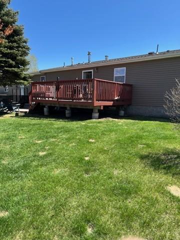 back of property featuring a lawn and a wooden deck
