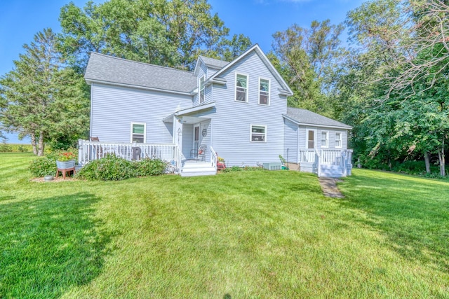 rear view of house with a lawn, a deck, and a shingled roof