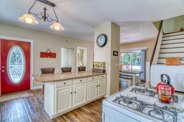 kitchen with a peninsula, light wood-type flooring, light countertops, a textured ceiling, and white gas range oven