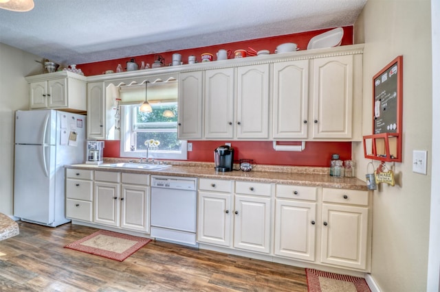 kitchen with a sink, white appliances, wood finished floors, and white cabinetry