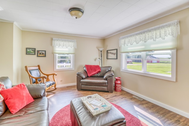 living room with crown molding, baseboards, visible vents, and wood finished floors