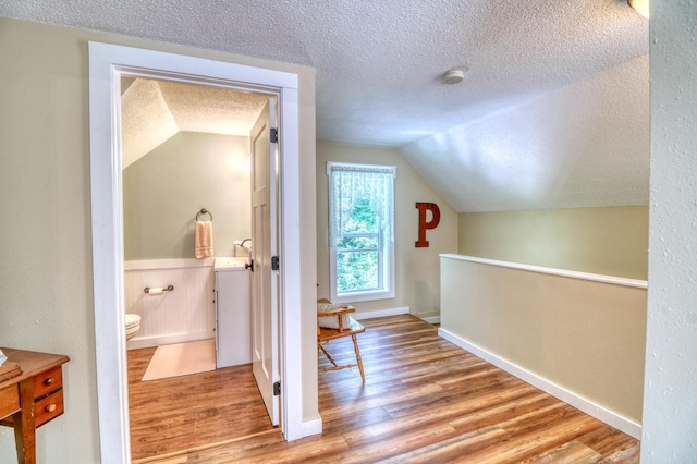 bonus room featuring baseboards, vaulted ceiling, a textured ceiling, and wood finished floors