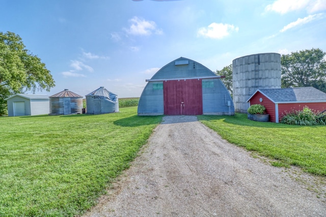 view of barn featuring a yard and dirt driveway