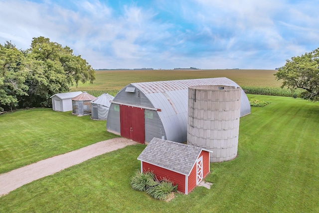 view of barn featuring a lawn, a rural view, and driveway