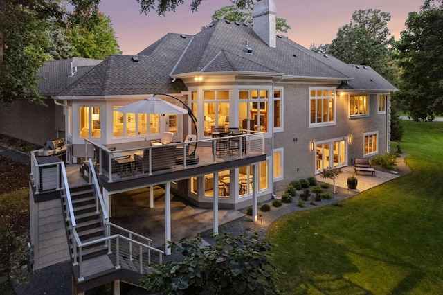2454 Crowne Hill Rd, Minnetonka, MN 55305 - back of property at dusk with a chimney, a lawn, a wooden deck, a patio area, and stairs