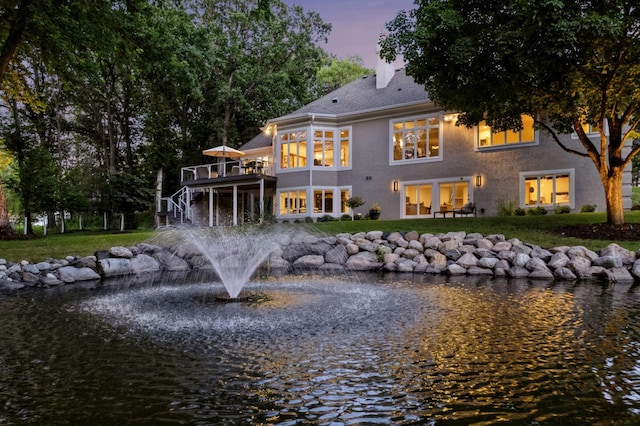 2454 Crowne Hill Rd, Minnetonka, MN 55305 - back of house at dusk with a lawn, stucco siding, a deck with water view, and a chimney
