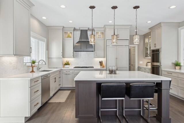 2454 Crowne Hill Rd, Minnetonka, MN 55305 - kitchen featuring a kitchen island, a breakfast bar area, wall chimney range hood, a sink, and stainless steel appliances