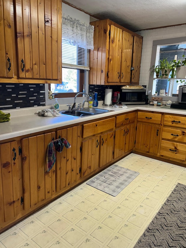kitchen with brown cabinets, a sink, light countertops, stainless steel microwave, and light floors