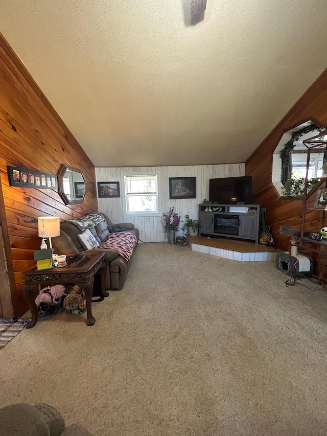 living area with wooden walls, vaulted ceiling, carpet flooring, and a textured ceiling