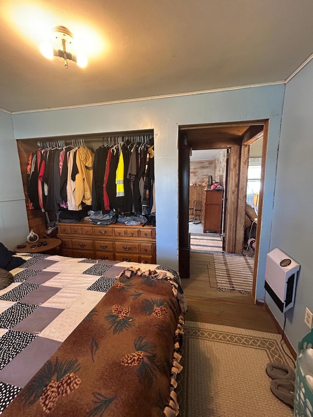 bedroom with heating unit and wood finished floors