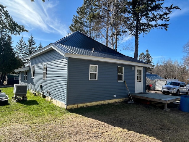view of home's exterior featuring a lawn, a deck, cooling unit, and metal roof