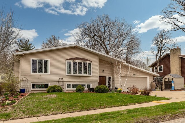 view of front of house with a garage, driveway, a front lawn, and a storage unit