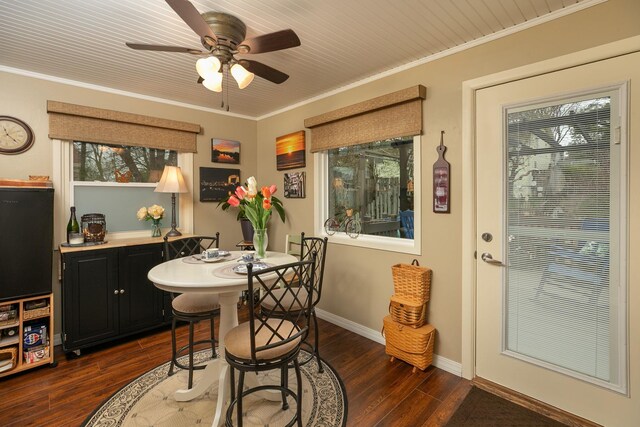 dining space featuring dark wood-type flooring, ceiling fan, crown molding, and baseboards