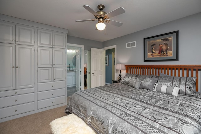 carpeted bedroom with ensuite bath, ceiling fan, and a closet