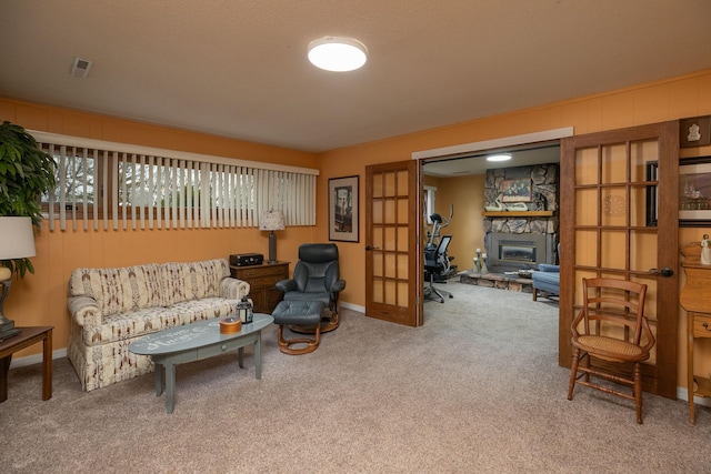 sitting room with carpet floors, baseboards, and a stone fireplace