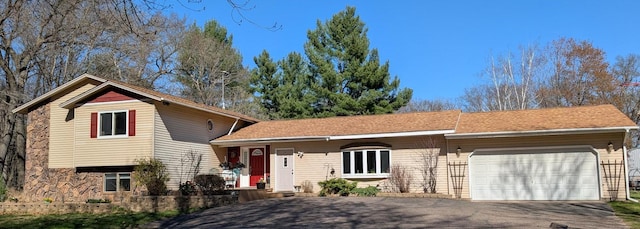 tri-level home with an attached garage and aphalt driveway