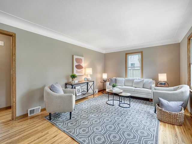 living room featuring wood finished floors, baseboards, and ornamental molding