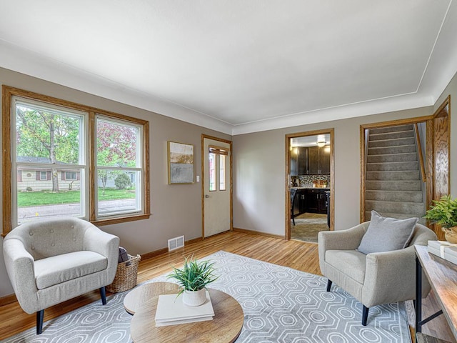 living room featuring light wood-style flooring, stairway, and baseboards